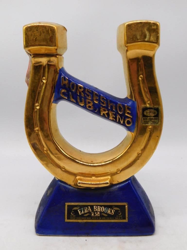 Ezra Brooks Horseshoe Club Reno Nevada Gold Horseshoe Decanter: An uncommon Ezra Brooks decanter cast as a gilt horseshoe set upright on a cobalt plinth HORSESHOE CLUB RENO raised in gold across a blue banner. The gold has kept a bright even luster and the cobalt 