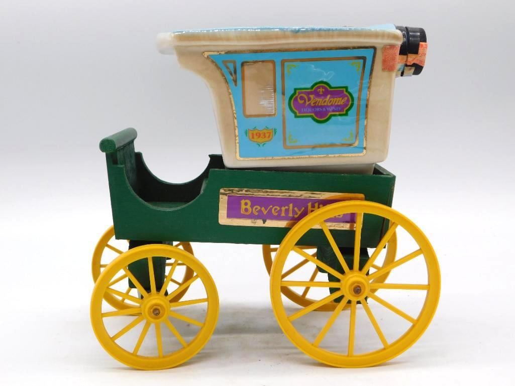 Jim Beam Vendome Beverly Hills 1937 Delivery Wagon Decanter Seal Intact: A Jim Beam Regal China decanter styled as a 1937 delivery wagon for Vendome Liquors & Wines Beverly Hills the green wooden-look cart body and yellow spoked wheels riding atop a blue and cream porcelai