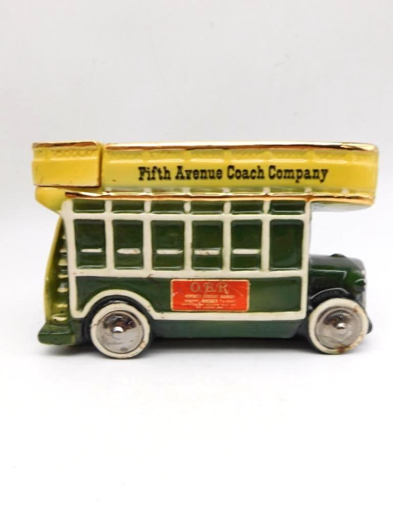 Fifth Avenue Coach Company Double-Decker Bus Decanter: A ceramic decanter modeled as an early open-top double-decker bus painted green and yellow with gilt trim along the roofline. The upper deck is marked Fifth Avenue Coach Company and an O.B.R. shield d