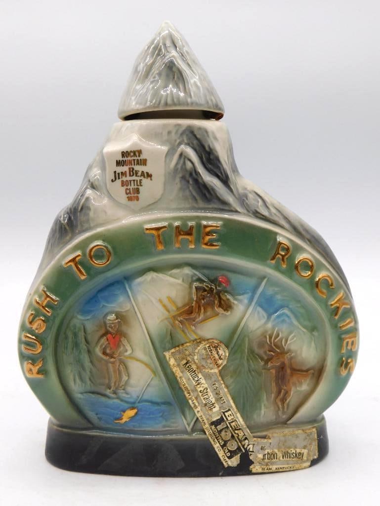 Jim Beam Rush to the Rockies Rocky Mountain Bottle Club Decanter 1970: A Jim Beam Rush to the Rockies decanter in green and gray made for the Rocky Mountain Jim Beam Bottle Club in 1970 this the third example offered. Relief ski and wildlife scenes wrap the body and the 