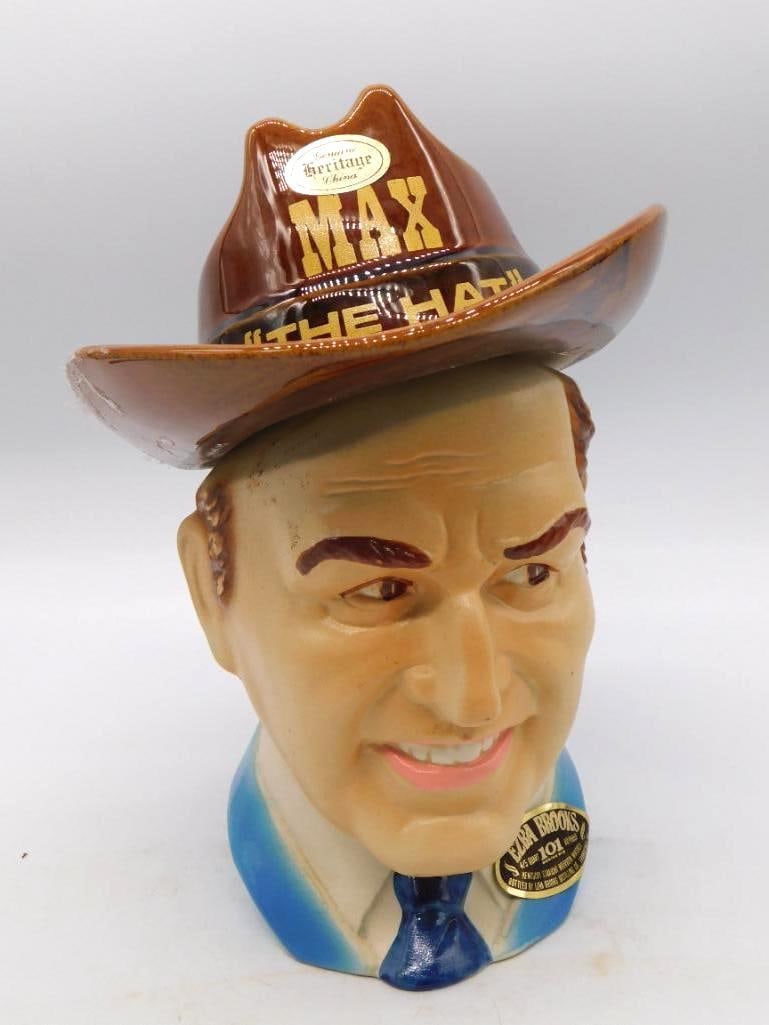 Heritage House Max the Hat Character Bourbon Decanter: A Heritage House ceramic decanter modeled as the smiling face of a man beneath a wide-brimmed brown hat marked Max the Hat upon a blue base with an Ezra Brooks-style gold medallion label. A quirky cha
