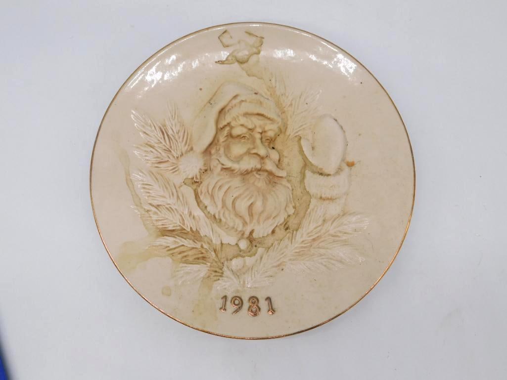 Vintage Santa Claus Ceramic Collector Plate 1981 Signed: A round ceramic collector's plate with a relief-molded portrait of Santa Claus dated 1981 and finished with a gilt rim. Hand-signed upon the reverse A.H. 'Steve' Stephenson. Not a decanter. Some surfa