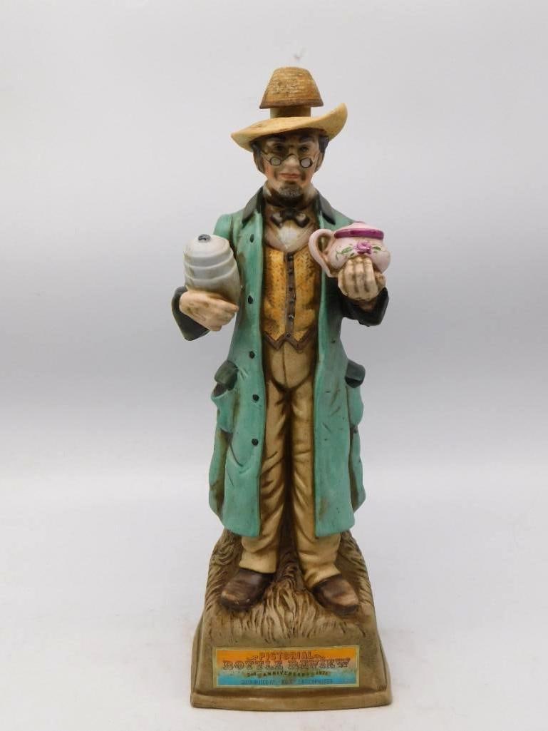 Pictorial Bottle Review 5th Anniversary 1973 Bottle Collector Decanter: A genial character decanter modeled as an old bottle collector in straw hat and wire spectacles a stoneware jug under one arm and a rose-painted creamer held out in the other hand. The green frock coa
