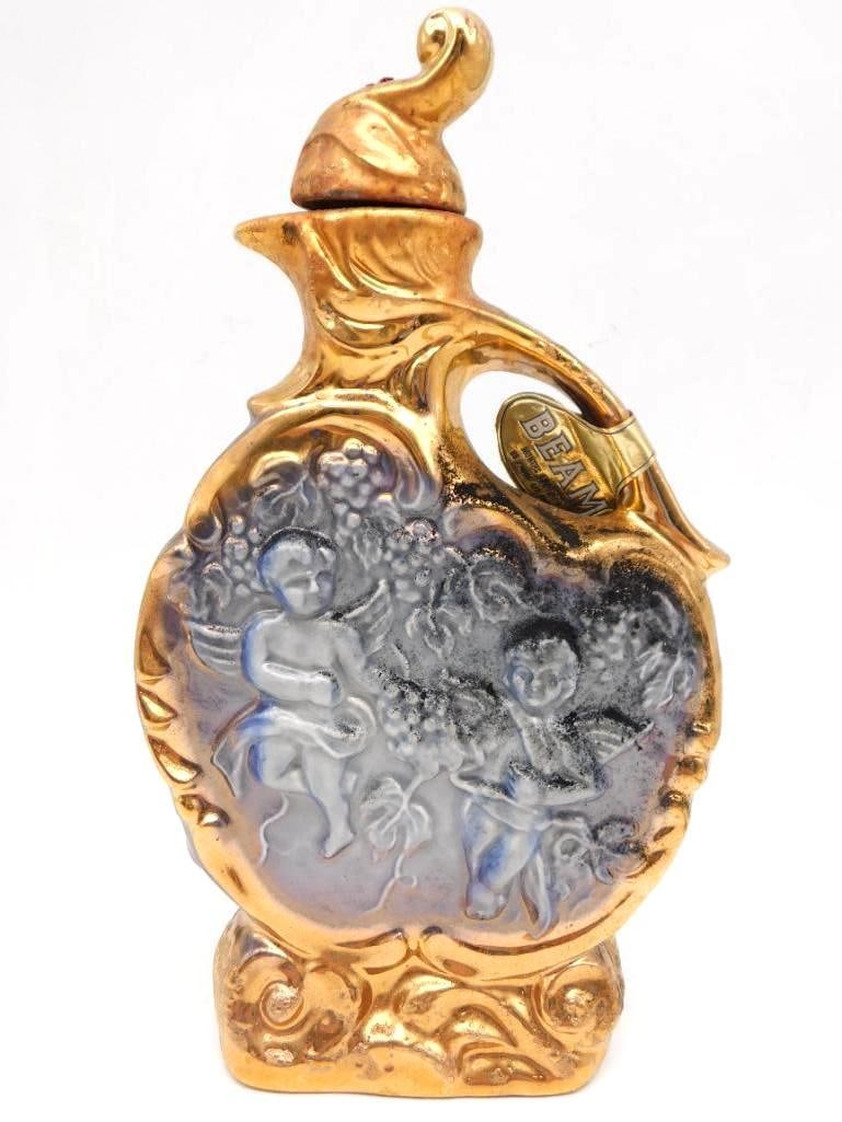 Jim Beam Cherub Regal China Decanter in Gold and Cobalt Companion Lot: A second Jim Beam Regal China cherub decanter in gold and cobalt matching the companion lot offered alongside it. Beam 100 months old Kentucky Straight Bourbon standing approximately 12 inches tall. H