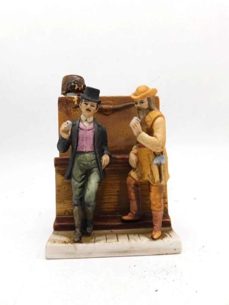 Small Porcelain Whiskey Bottle Two Men at the Counter Made in Japan: A small hand-painted porcelain whiskey bottle modeled as two men in conversation one in a top hat and pink vest the other in mountain-man attire. Marked Made in Japan to the base. The cork stopper is