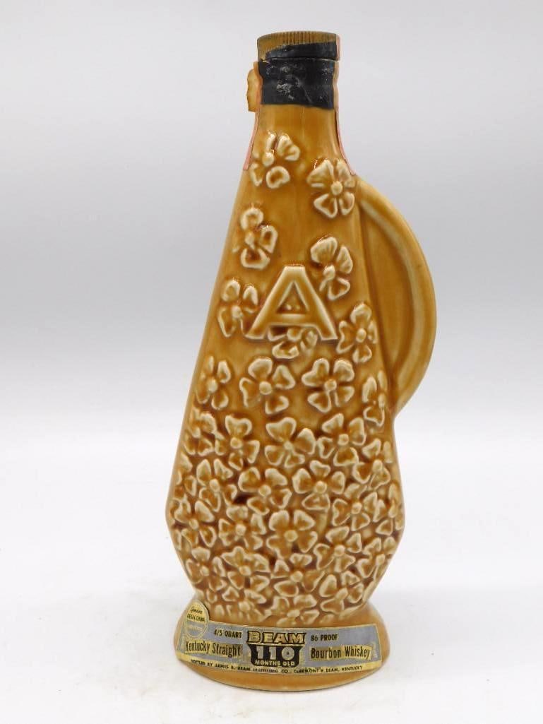 Jim Beam Regal China Amber Floral Kentucky Bourbon Decanter: A Jim Beam Regal China decanter under an amber glaze worked all over with a raised daisy pattern that rewards a close look. Labeled Kentucky Straight Bourbon Whiskey 110 months old 86 proof. An agreea