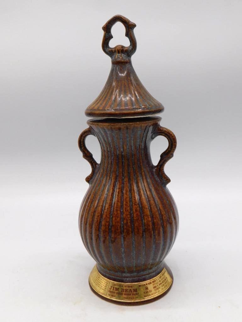 Jim Beam Bottled in Bond 8 Years Urn-Form Decanter Brown Drip Glaze: A Jim Beam Bottled in Bond 8 Years Old Kentucky Straight Bourbon Whiskey decanter in an urn form with twin handles and a fitted lid finished in a brown and blue drip glaze. A sober and stately shape t