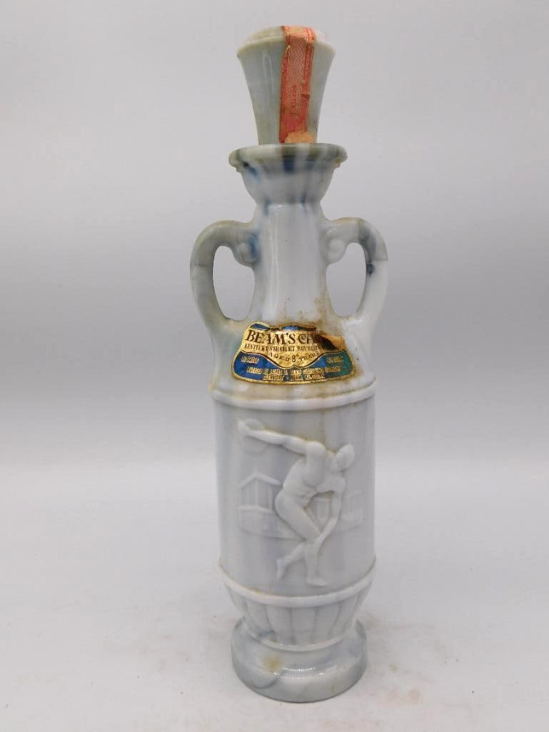 Jim Beam Marbled Blue Glass Classical Athlete Amphora Decanter: A trim Jim Beam decanter in the form of a two-handled amphora the glass swirled in smoky blue and gray with a classical athlete cast in white relief upon the body. A sober and well-turned shape more
