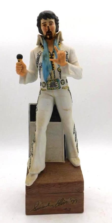 McCormick Elvis Presley Sincerely Elvis '77 Music Box Decanter: A McCormick decanter modeled as Elvis Presley in the white jumpsuit microphone raised and a blue scarf about his neck an amplifier standing behind him. The bisque is nicely detailed in the belt and th
