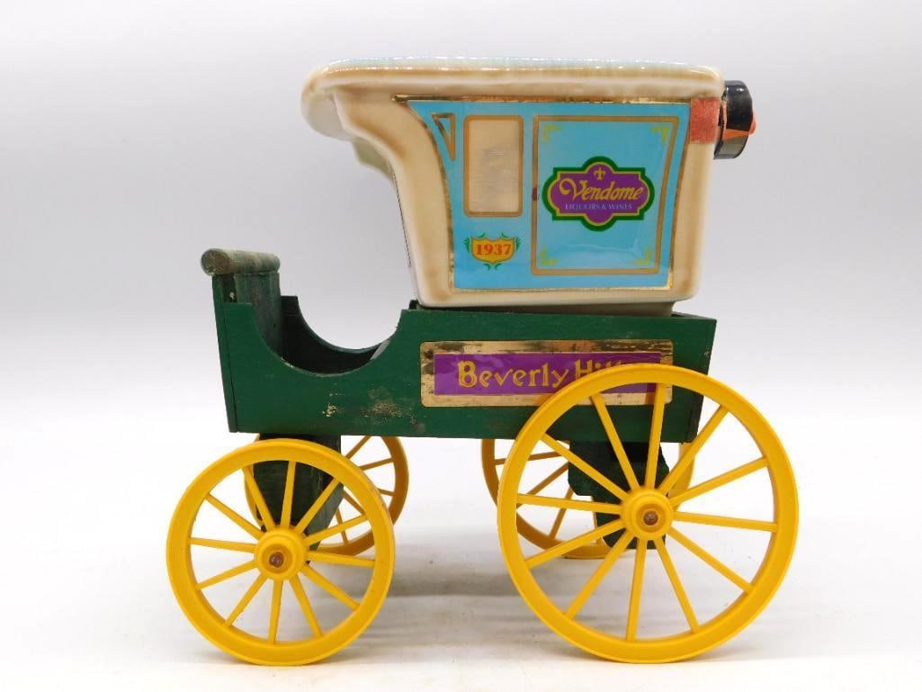 Jim Beam Vendome Beverly Hills 1937 Delivery Wagon Decanter: A second example of the Jim Beam Vendome Liquors & Wines Beverly Hills delivery wagon decanter its green wooden cart running on yellow wheels beneath a blue and cream porcelain barrel body. Marked Bea