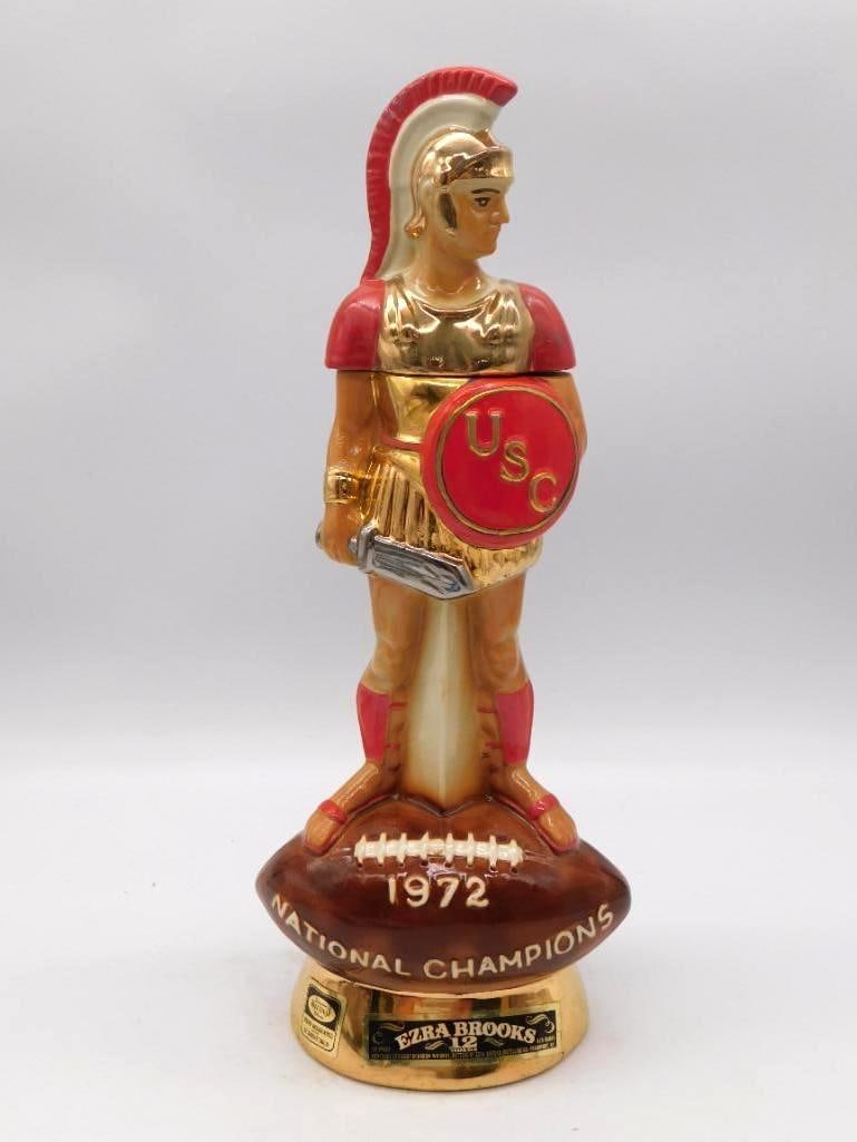 Ezra Brooks USC Trojans 1972 National Champions Football Decanter: A commanding Ezra Brooks decanter in gold and red modeled as the USC Trojan mascot standing upon a football base inscribed 1972 NATIONAL CHAMPIONS. The reverse carries the USC football history