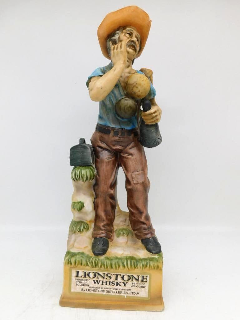 Lionstone The Tinker Old West Series Decanter Seal Intact: A homespun Lionstone decanter from the Old West series modeled as The Tinker an itinerant mender hung about with kettles pans and a lantern one hand cupped to his mouth as he calls the street. The rev