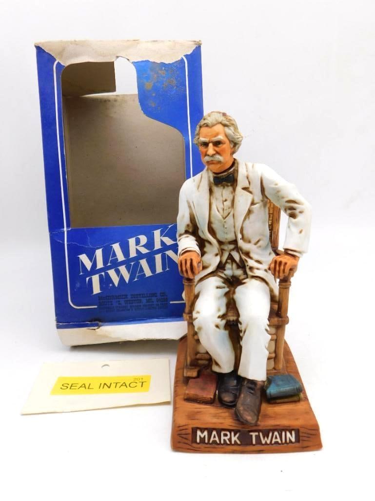 McCormick Mark Twain Americana Porcelain Decanter Seal Intact with Original Box: A McCormick decanter modeled as Mark Twain seated at his ease in a cane-backed rocker books at his feet and the plinth lettered MARK TWAIN. The face is caught with genuine character. Approximately 12