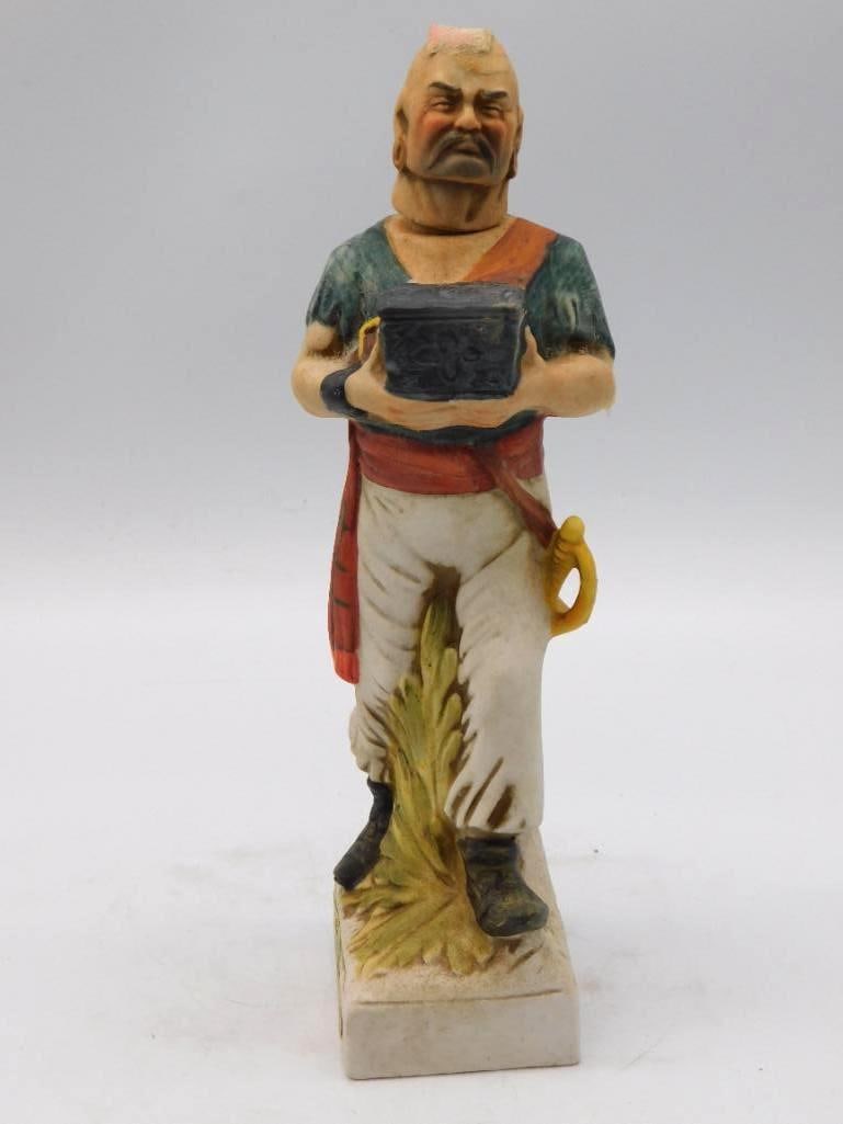 McCormick Rum West Indies Pirate Decanter with Cutlass Seal Intact: A ceramic decanter cast as a pirate with a chest under one arm and a cutlass at the ready marked McCormick Rum distilled in the West Indies. A rakish character sharply modeled and brightly painted.