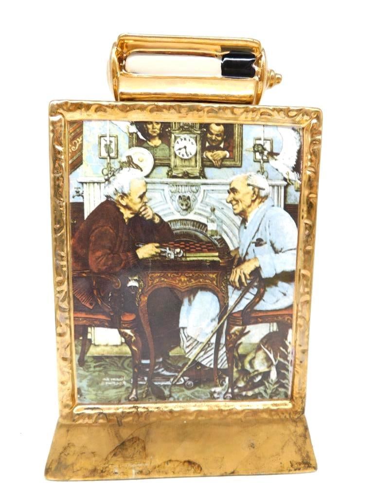 Norman Rockwell April Fools Saturday Evening Post Decanter 23K Gold: A ceramic decanter cast as a gilt picture frame carrying Norman Rockwell's April Fools cover for The Saturday Evening Post of April 3 1943 two old gentlemen at checkers in a room full of deliberate