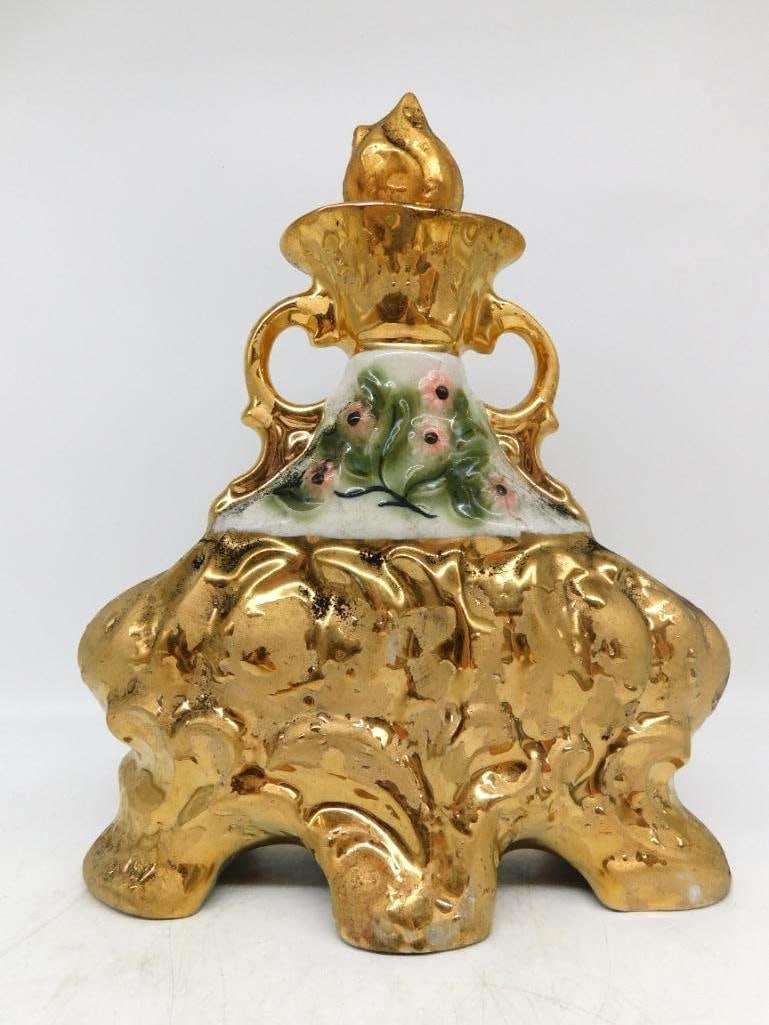 Gold Luster Twin-Handled Urn Decanter with Painted Blossoms Seal Intact: A stately urn-form decanter in heavy gold luster twin scroll handles at the shoulder and a flame-shaped stopper above. A white reserve at the neck carries hand-painted pink blossoms and green leaves a