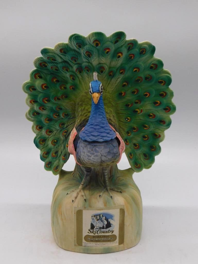 Ski Country Peacock Bourbon Whiskey Decanter: A Ski Country hand-painted porcelain decanter modeled as a peacock in full display the tail feathers vividly colored and still strong. The original paper label remains to the base. Minor age wear only