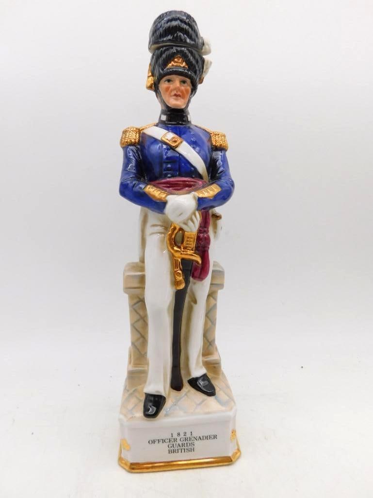 1821 British Officer Grenadier Guards Porcelain Soldier Decanter: A commanding porcelain decanter modeled as an officer of the British Grenadier Guards resplendent in blue coat with gold epaulettes crimson sash white trousers and a tall bearskin that lifts away as t