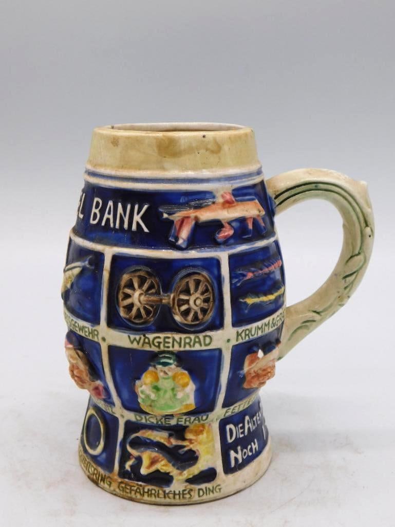 German Ceramic Relief Beer Stein Tankard Comic Village Scene: A German ceramic beer stein and tankard worked in allover molded relief with comic village scenes and German captions among them Wagenrad Bank and Dicke Frau in blue cream and gold. The mold work is l