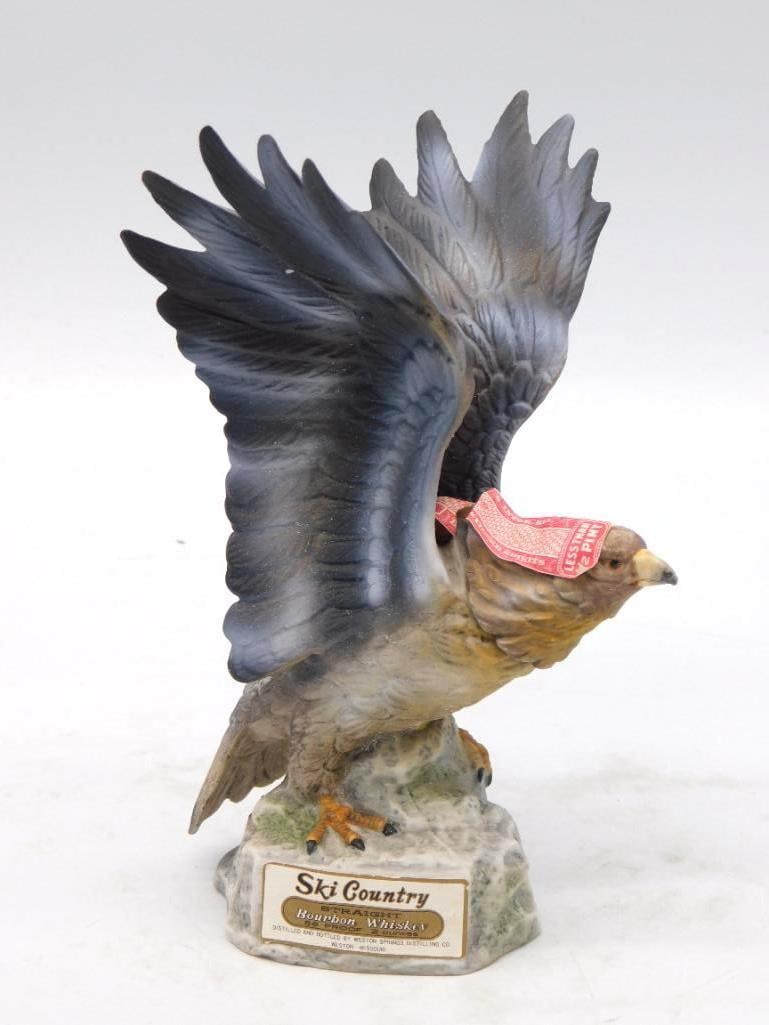 Ski Country Bird of Prey Decanter Wings Upswept on Rocky Perch: A handsome Ski Country decanter modeled as a bird of prey alighting upon a stone outcrop wings thrown high and talons set. The feathering is carved deep and painted in sober grays and browns and the b