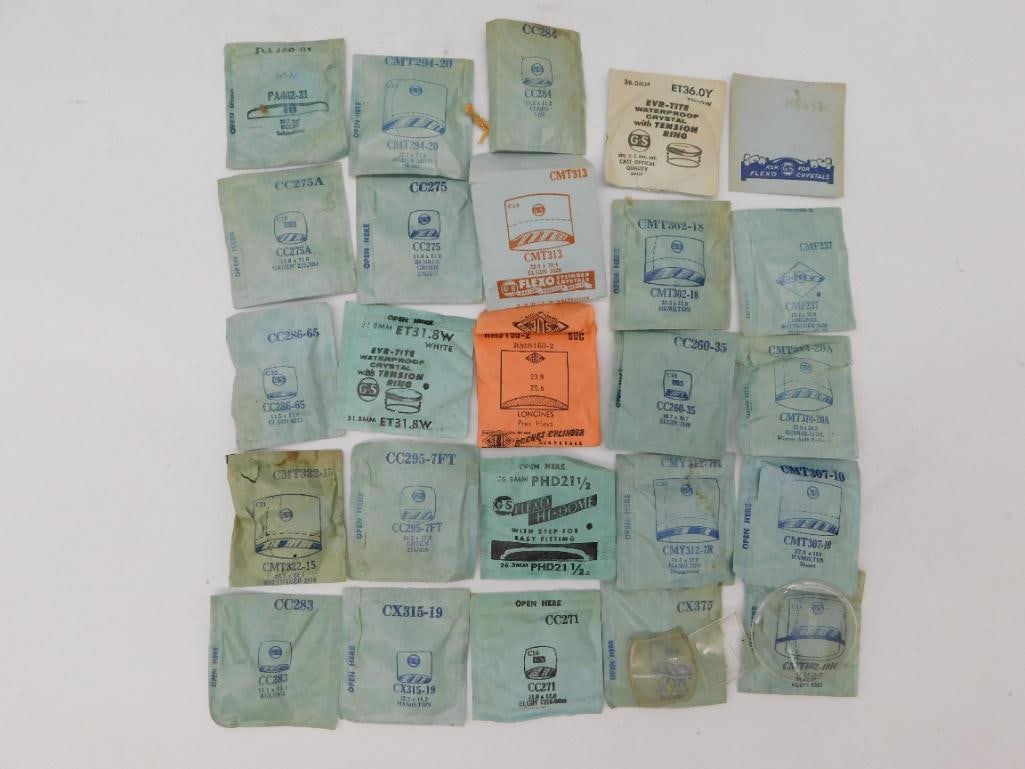Watch Parts: Vintage Crystal Lot in Original Envelopes: Approximately 25 vintage watch crystals in original G-S and other manufacturer paper envelopes, plus several loose glass crystals including a large round example and a rectangular Elgin-fitted crystal