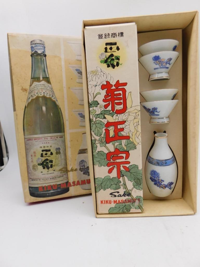 Kiku-Masamune Japanese Sake Gift Set with Bottle and Cups: Vintage Kiku-Masamune Japanese sake gift set in original illustrated box, including a glass sake bottle, a ceramic sake flask, and three hand-painted porcelain cups with blue floral and gold trim. Box