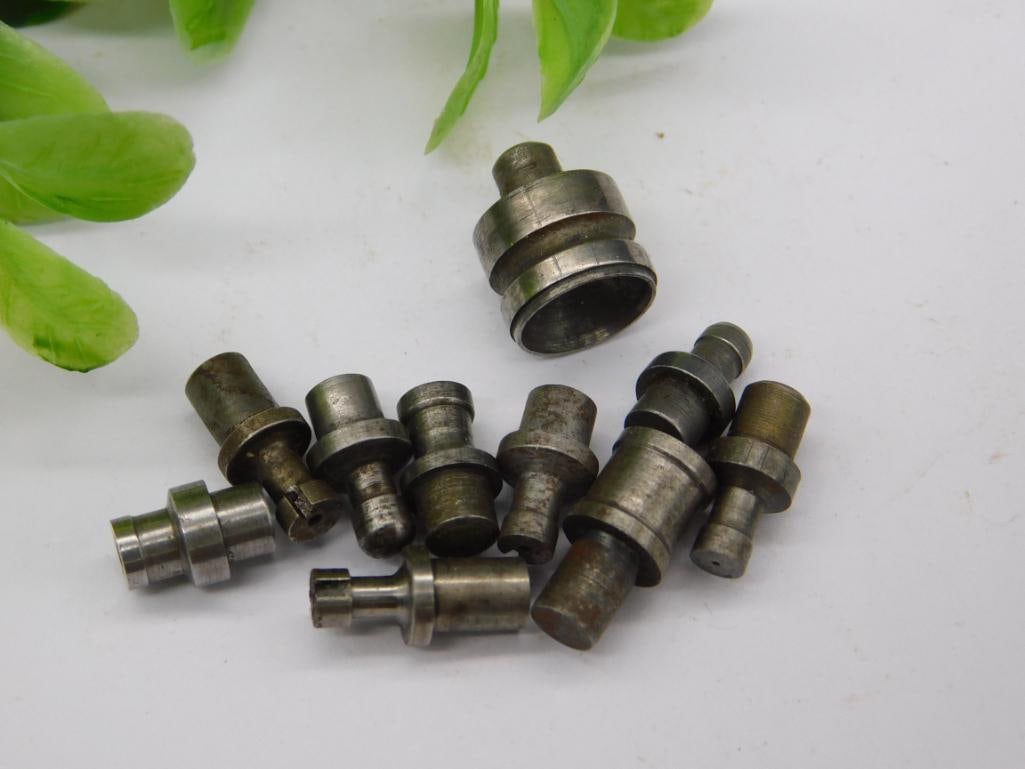 Watchmaker Staking Dies with Large Cup Punch (9 pcs): Nine watchmaker staking set punches and dies, including one large hollow cup-shaped die and several threaded or grooved shanks, in a worn steel finish. Used for watch case and jewel work on a staking