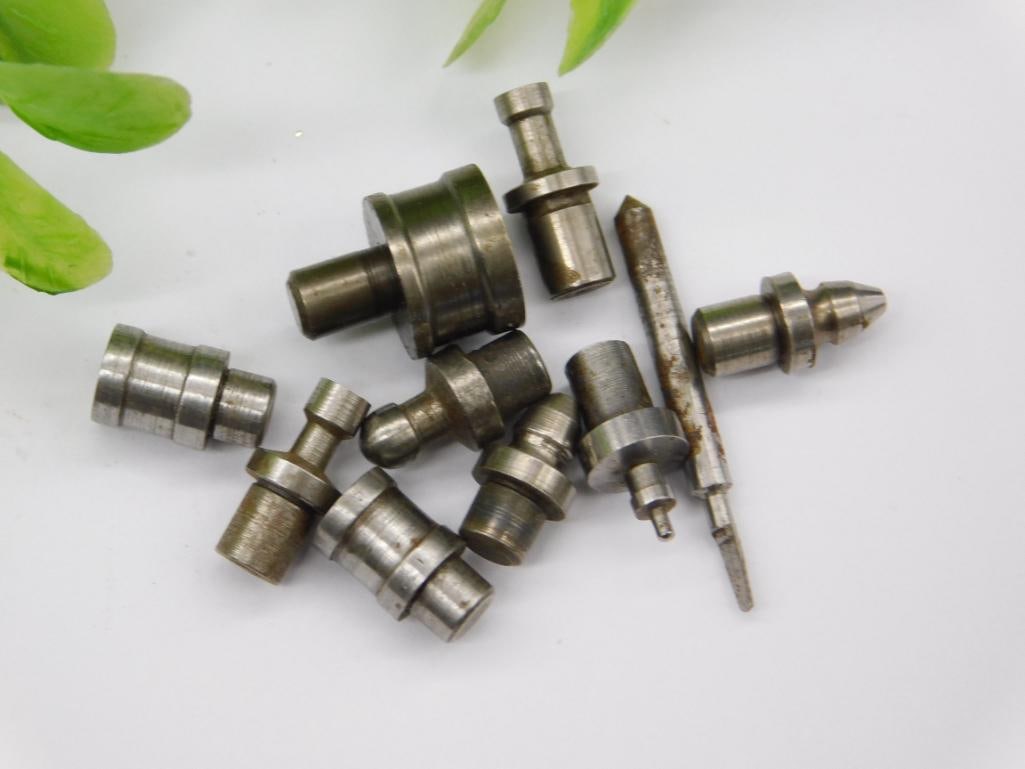 Watchmaker Staking Tool Parts with Coin for Scale: Assortment of small steel punches/stakes with a screwdriver-shaped forked bit and stepped shafts featuring pointed and cupped tips. Unmarked, with light surface rust on a few pieces.