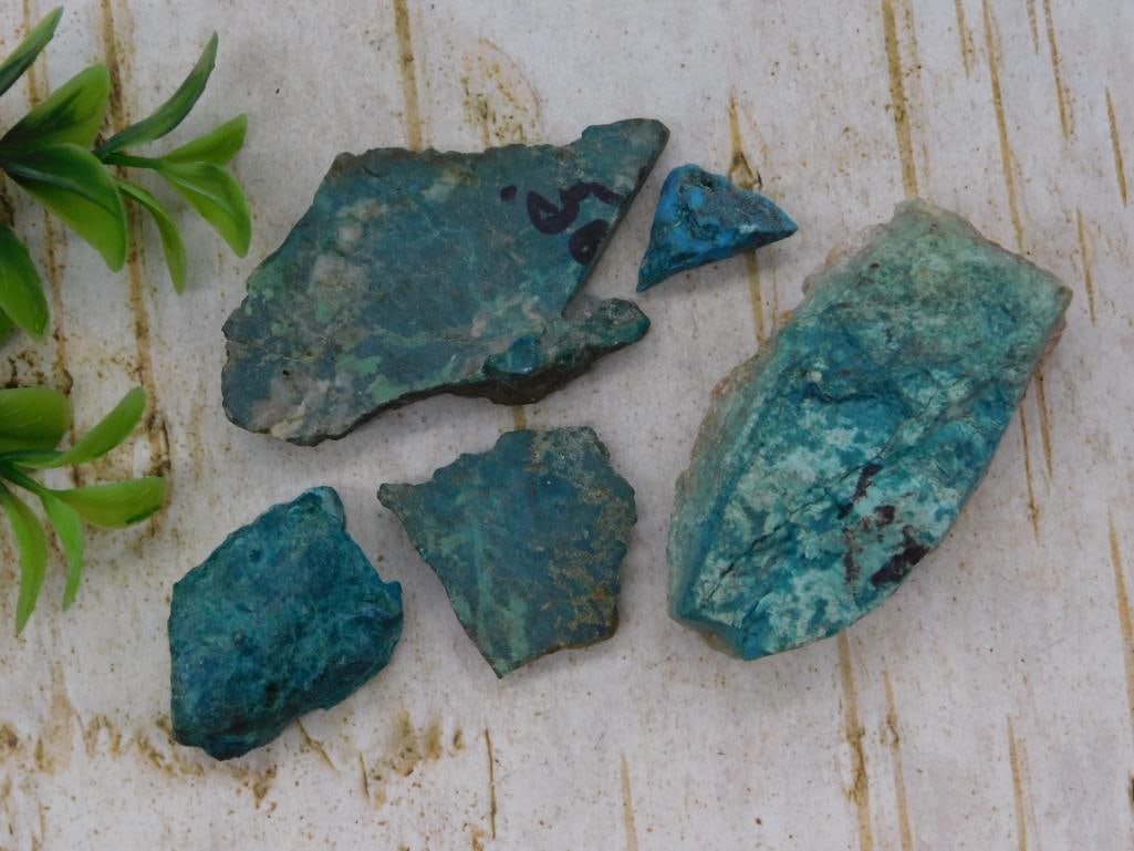 Rock - Chrysocolla Rough Specimen Lot: Lot of five rough chrysocolla stone slabs and chunks in saturated teal and blue-green with darker matrix veining, one piece bearing a faded grease-pencil inventory number. Combined weight is 59 grams 