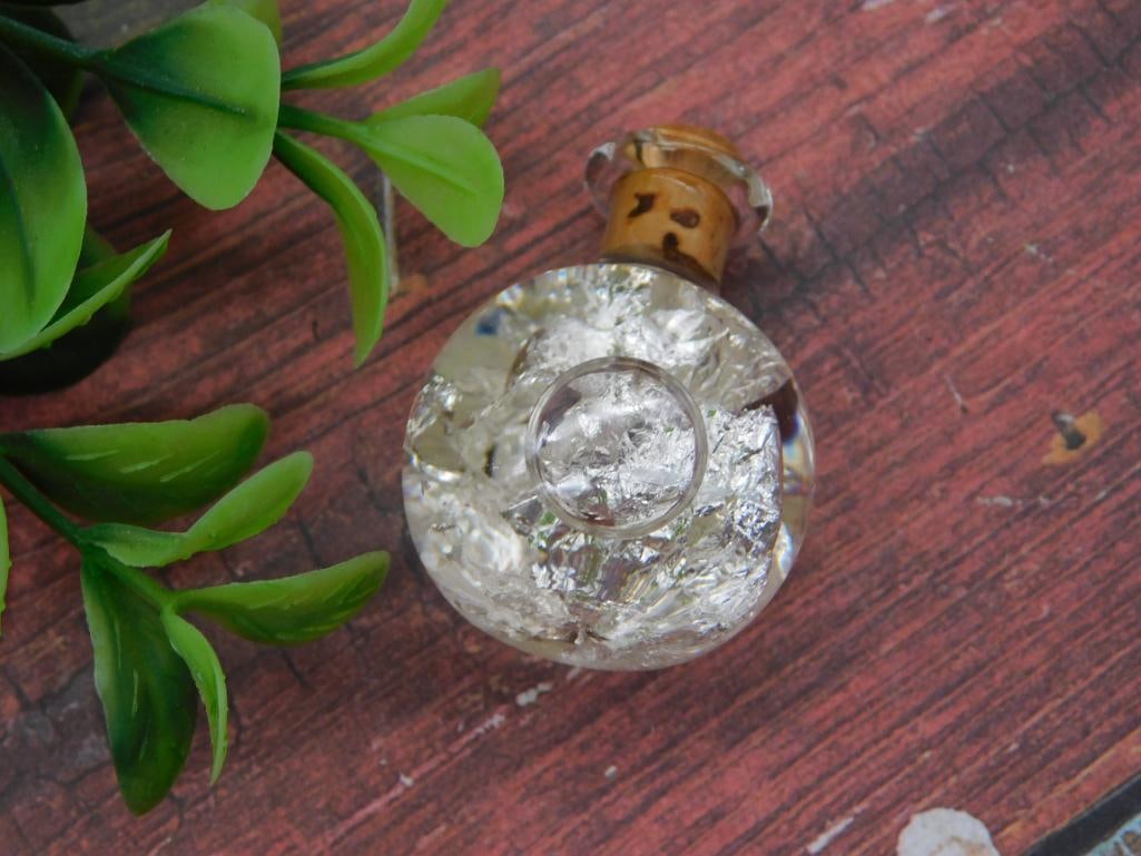 Antique Foil-Filled Glass Perfume Bottle with Cork Stopper: Small round glass bottle filled with crinkled silver foil, sealed with an aged cork stopper. Vintage decorative or perfume bottle, approximately 1.5 inches in diameter, shown beside a 1966 quarter for