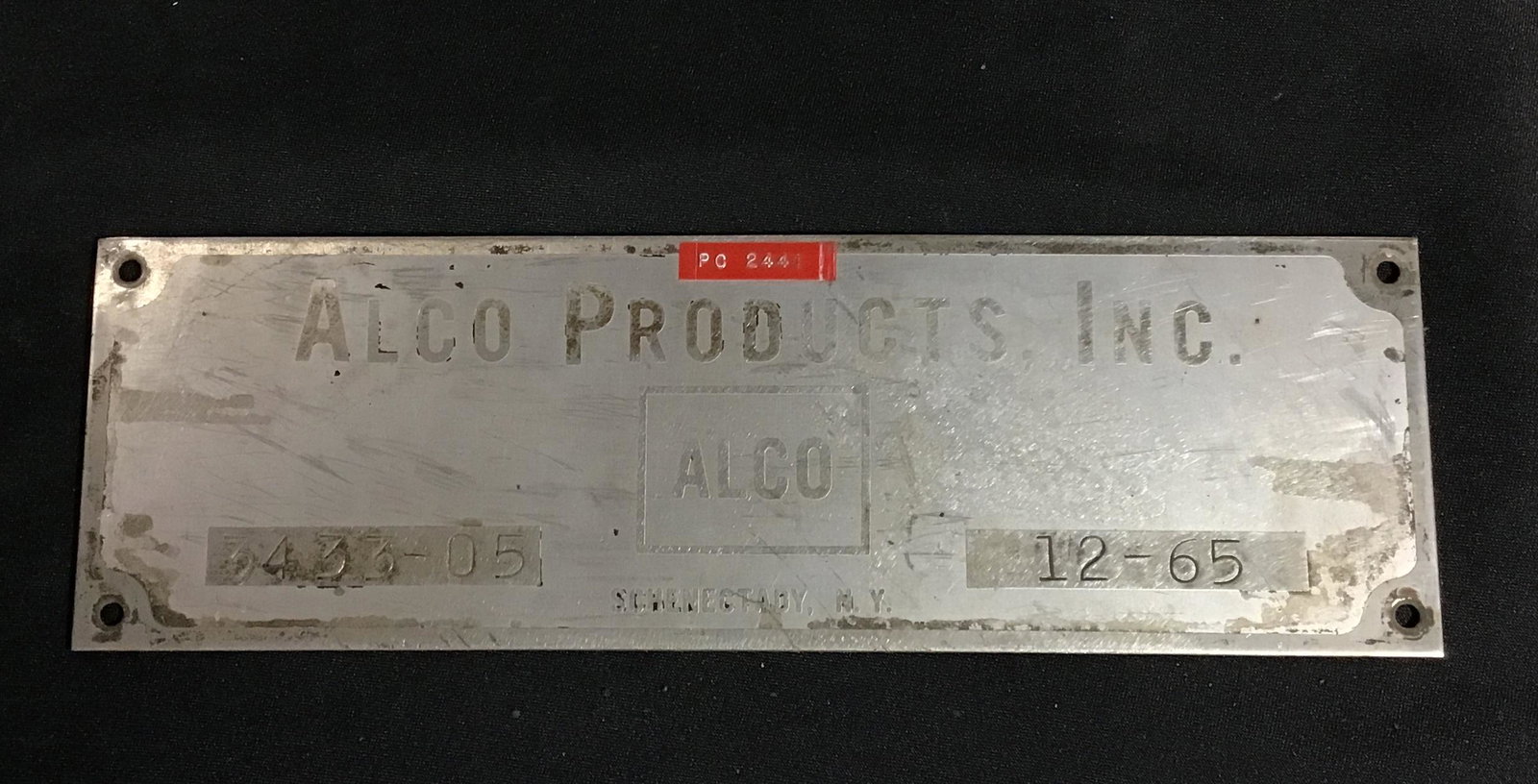 19 65 Alco products Inc. sign, PC number 2441 Measures 12 inches in length 4 inches in height: 2441 Measures 12 inches in length 4 inches in height