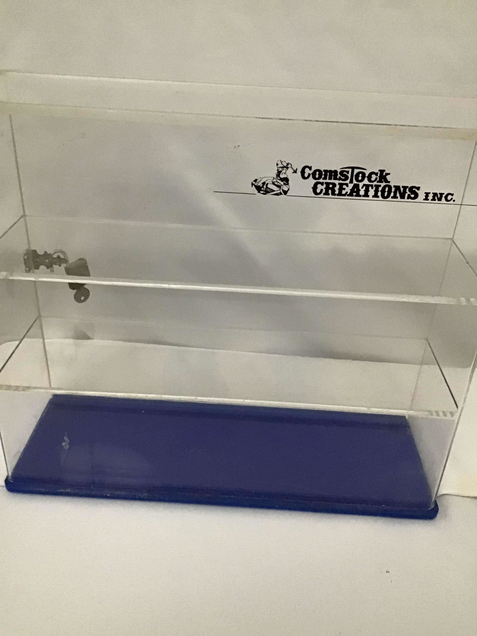Comstock Creations Collectible Plexiglass Showcase with two shelves and lockable. Sliding access: with two shelves and lockable. Sliding access back door measures 12 1/2. By 14 x 5