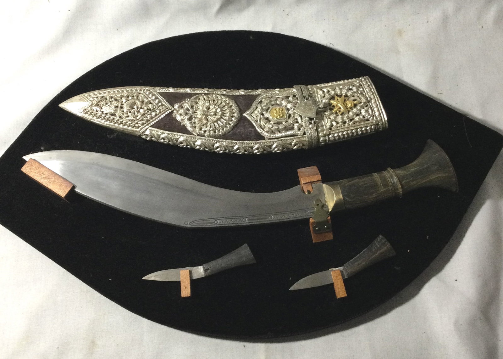 GURKHA KUKRIS Display Collection: complete with scabbard feature horn and brass handles and well wrought steel blades. Scabbard is covered with pierced silver decoration with winged animals or peacocks with a floral motif .Large blade