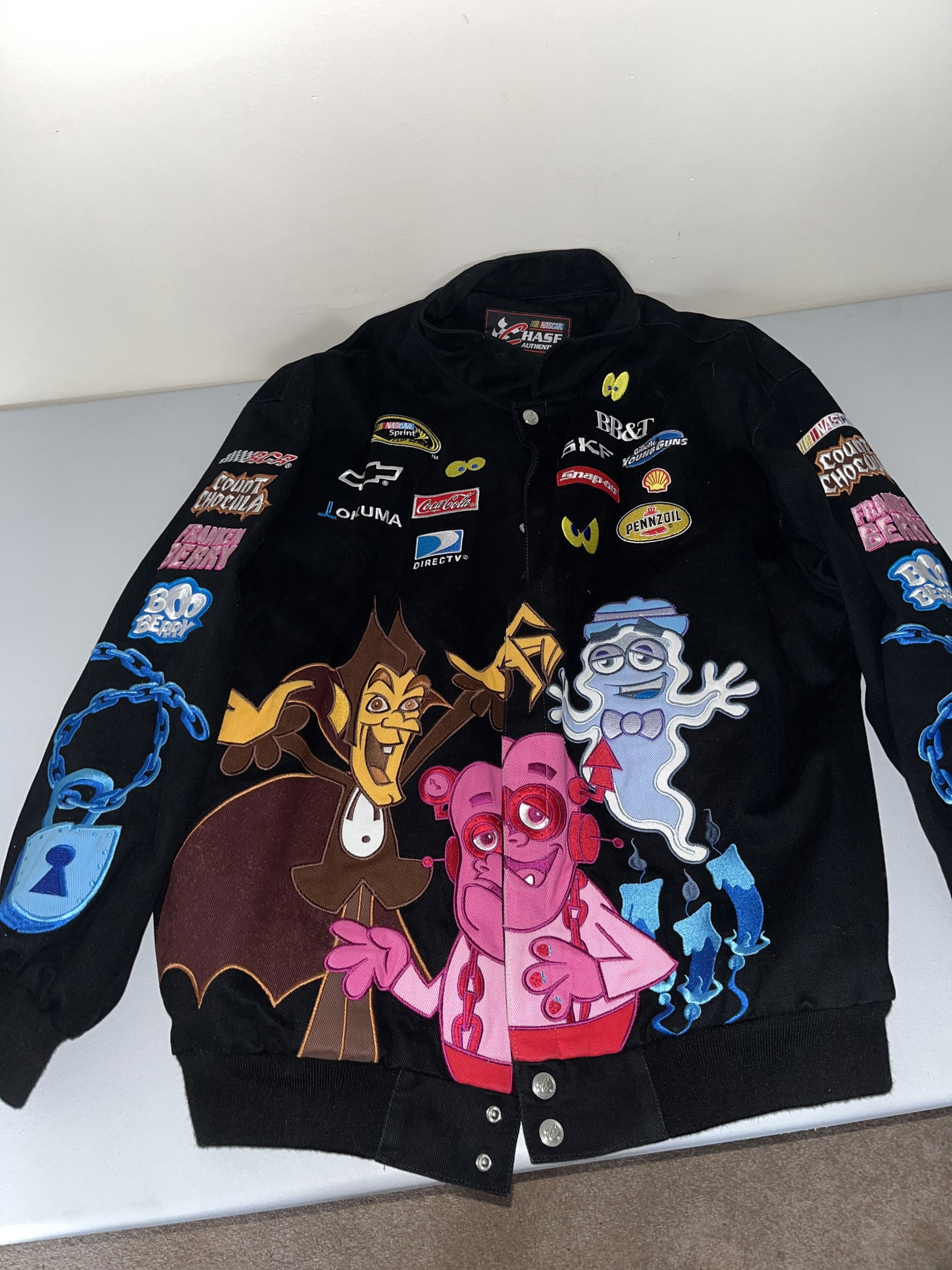 Chase Authentics NASCAR Clint Bowyer #33 Monster Cereals Driver Jacket XL: Chase Authentics officially licensed NASCAR Sprint Cup Series driver jacket. This garment is constructed with a heavy black cotton twill shell and a full polyester satin-finish lining featuring a repe