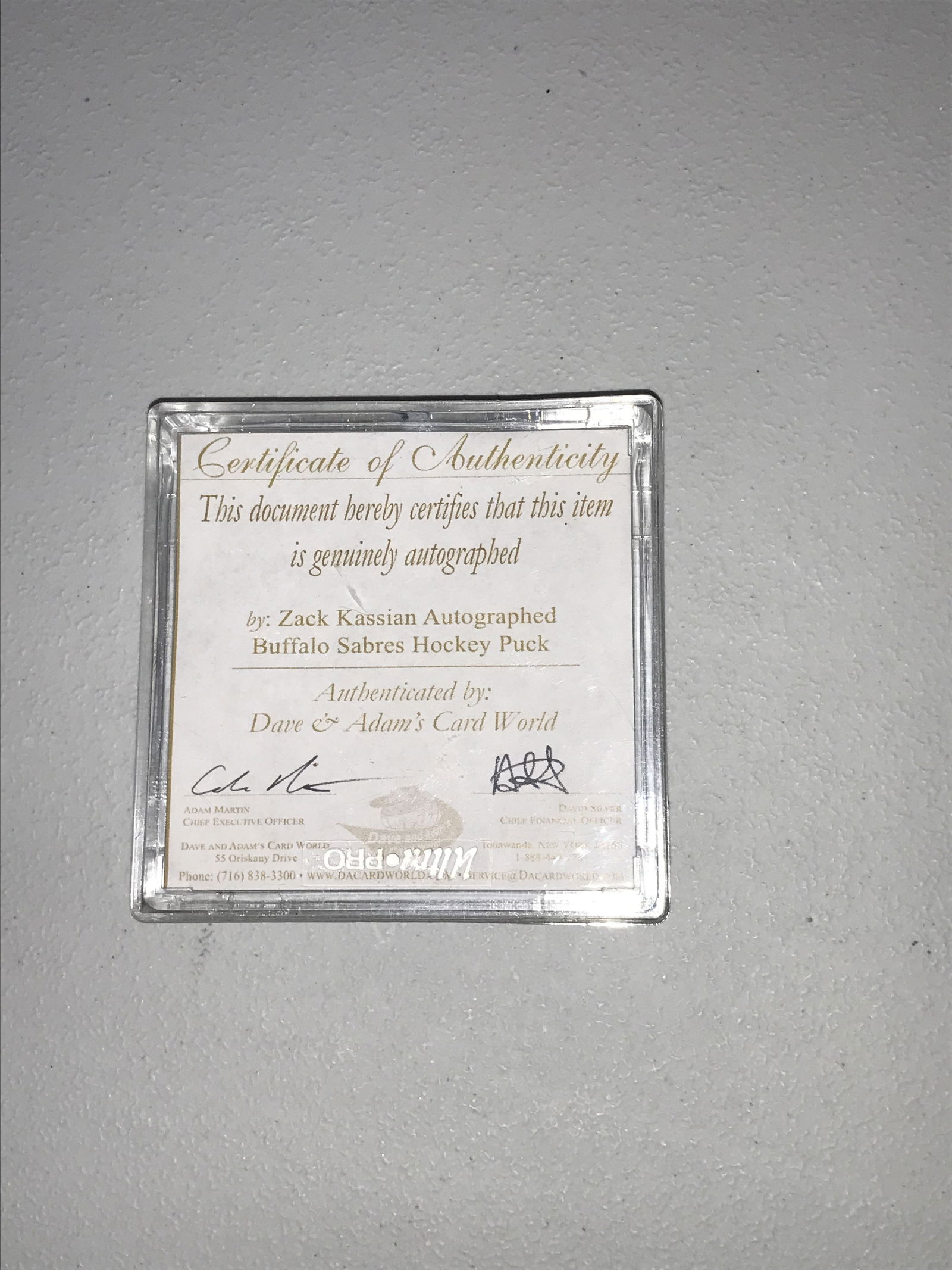 Zack Kassian Autographed Buffalo Sabres Hockey Puck: Zack Kassian autographed Buffalo Sabres hockey puck, circa 2011-2012. The black regulation-style puck features the Buffalo Sabres logo on the front face and a signature in gold-tone metallic ink with