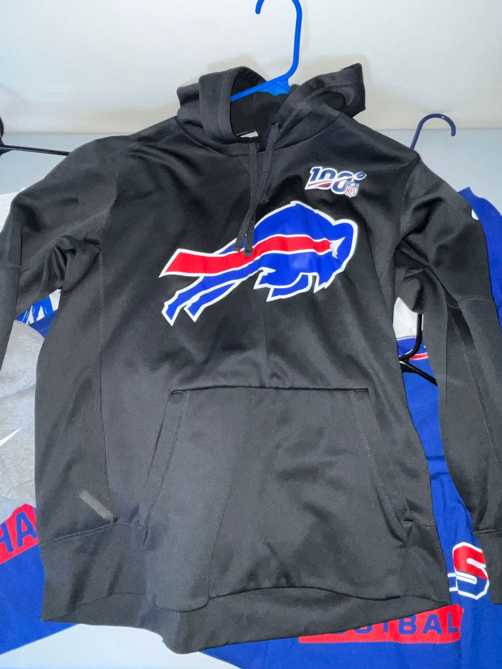 Buffalo Bills, Mixed Apparel Lot, Unsigned: This collection of Buffalo Bills fan apparel includes six individual pieces of team-branded clothing. The lot features one black hoodie with a large charging buffalo logo and the official NFL 100th An