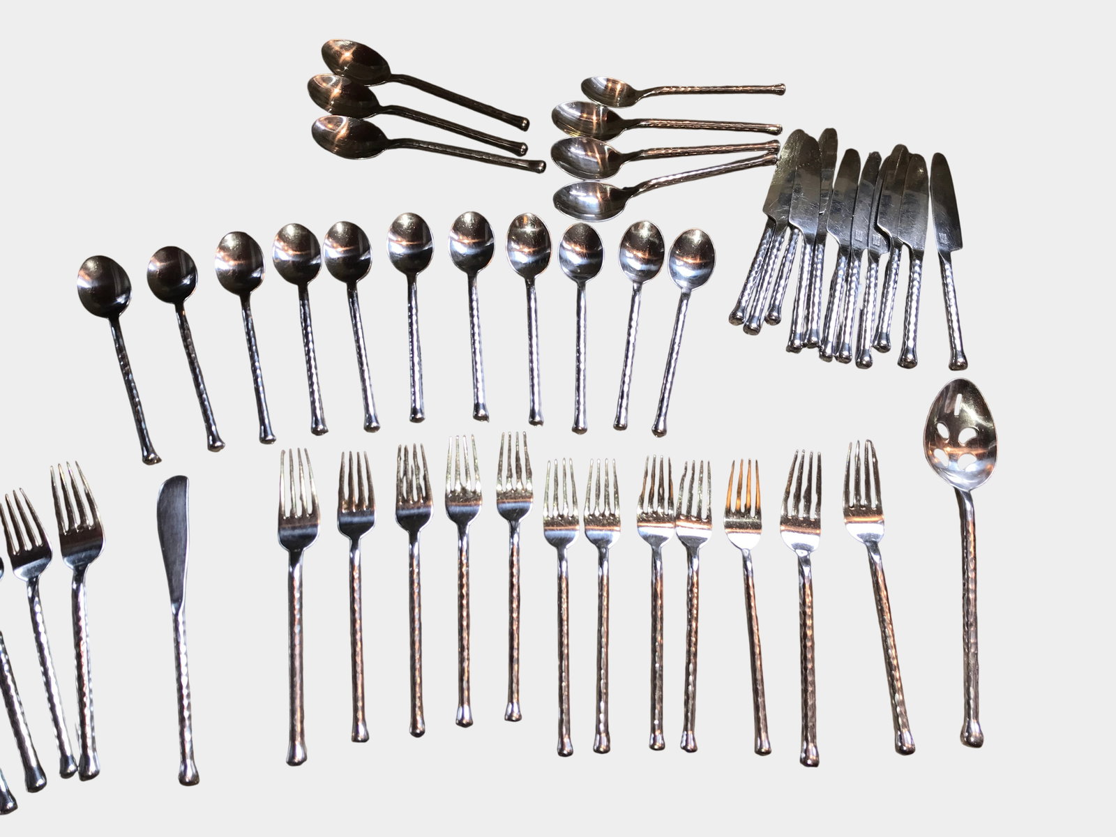 Set of Gourmet Settings Hammered Stainless Steel Flatware: Contemporary flatware service manufactured by Gourmet Settings. The pieces are crafted from 18/8 stainless steel and feature a hammered texture throughout the handles. The design is characterized by