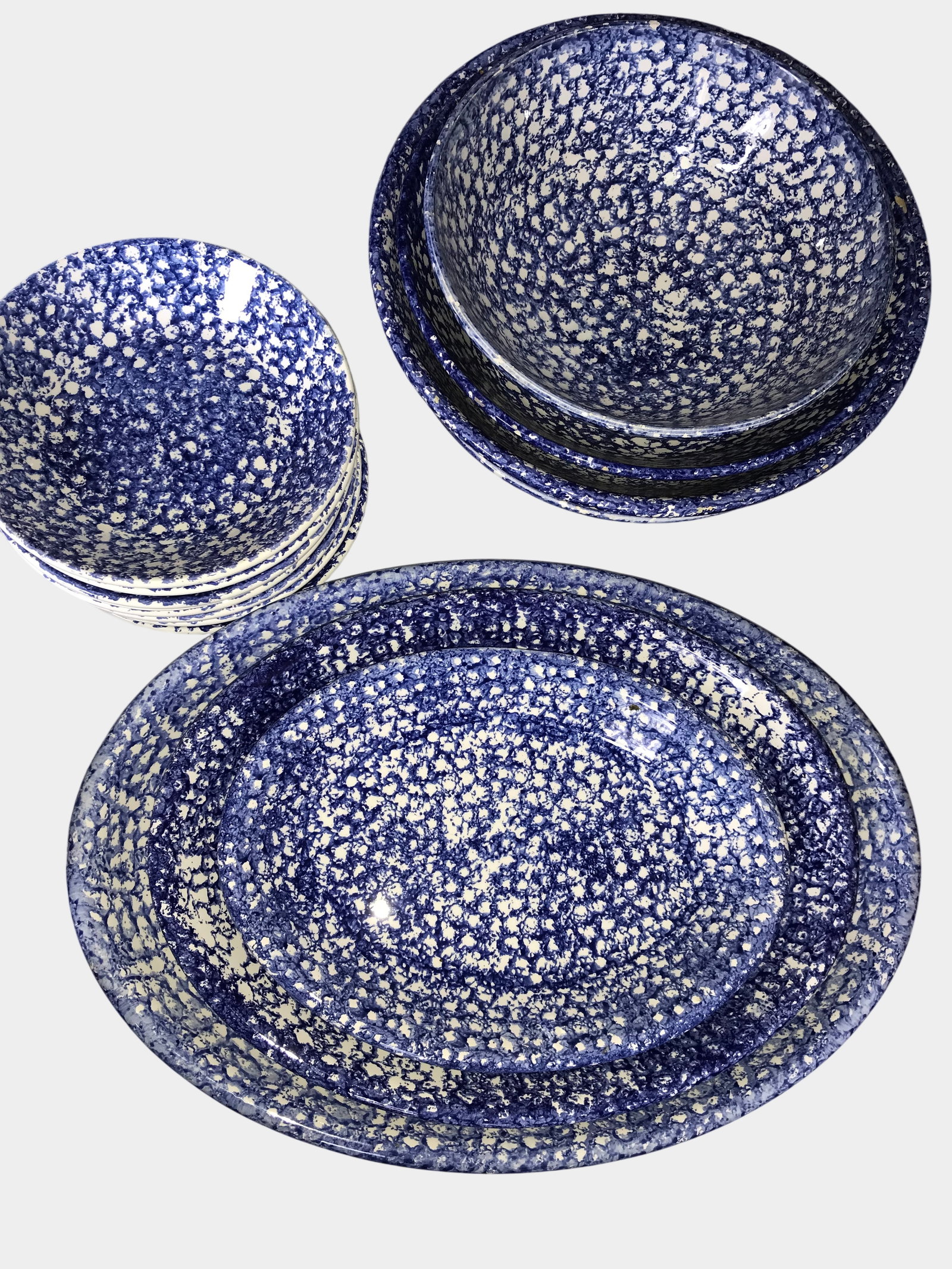 Blue and White Sponge-Decorated Earthenware: This collection of blue and white sponge-decorated earthenware features a mottled blue underglaze application over a cream-colored body. The group includes three graduated nesting bowls with rounded s