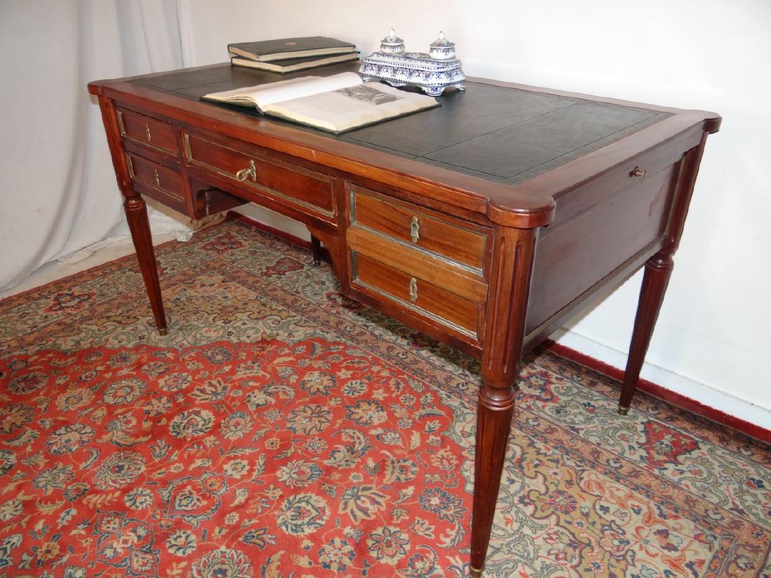 LOUIS XVI STYLE MAHOGANY BUREAU PLAT: LOUIS XVI STYLE MAHOGANY BUREAU PLAT HAVING BLACK AND GOLD TOOLED LEATHER TOP AND TWIN WRITING SLIDES OVER 5 LOCKING DRAWERS (WITH KEY) RESTING ON TRUNED FLUTED TAPERD LEGS AND BRONZE CAPPED FEET; 50"