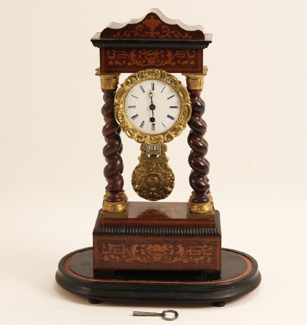 MARQUETRY INLAID FRENCH PORTICO CLOCK: MARQUETRY INLAID FRENCH PORTICO CLOCK HAVING BARLY TWIST AND GILT BRASS CORINTHIAN CAPS, EMBOSSED CHAPTER RING, ENAMEL DIAL, WITH ORIGINAL ADJUSTABLE PENDELUM AND KEY, 19TH C.; 17.5"H X 8.5"W X 5"D; C
