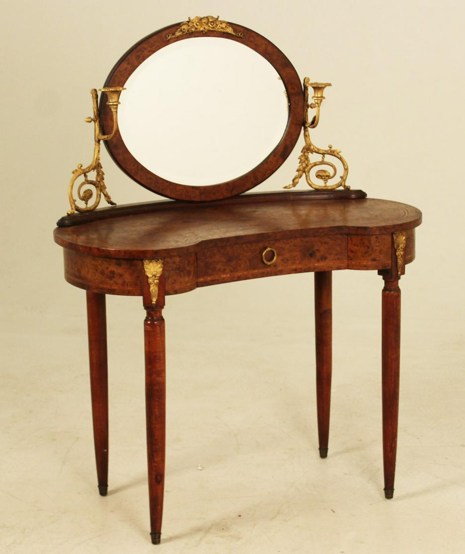 FRENCH BRZ MTD KIDNEY SHAPED DRESSING TABLE: FRENCH NAPOLEONIC STYLE INFLUENCED AMBOYNA BURL VENEERED KIDNEY SHAPED DRESSING TABLE WITH BRONZE CANDELABRA AND OVAL MIRROR BACK HAVING ONE DRAWER FRIEZE ON TAPERD TURN LEGS, LATE 19TH/20TH C.; 29"H 