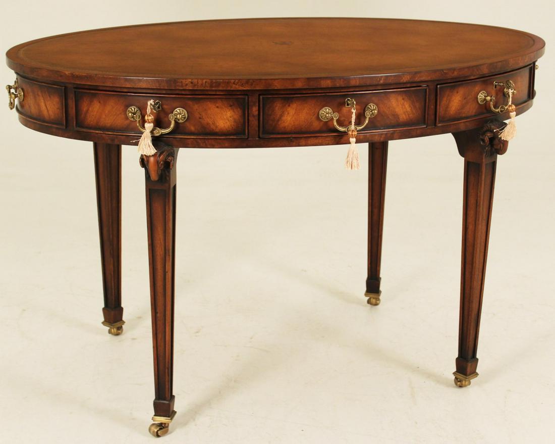 ENGLISH REGENCY STYLE OVAL MAHOGANY WRITING TABLE: ENGLISH REGENCY STYLE OVAL MAHOGANY WRITING TABLE WITH TOOLED LEATHER TOP AND 3 DRAWER FRIEZE RESTING ON RAMS HEAD CARVED MARBORO LEGS AND BRASS CASTERS (ALTHORPE COLLECTION); 30"H X 48"W X 35"D