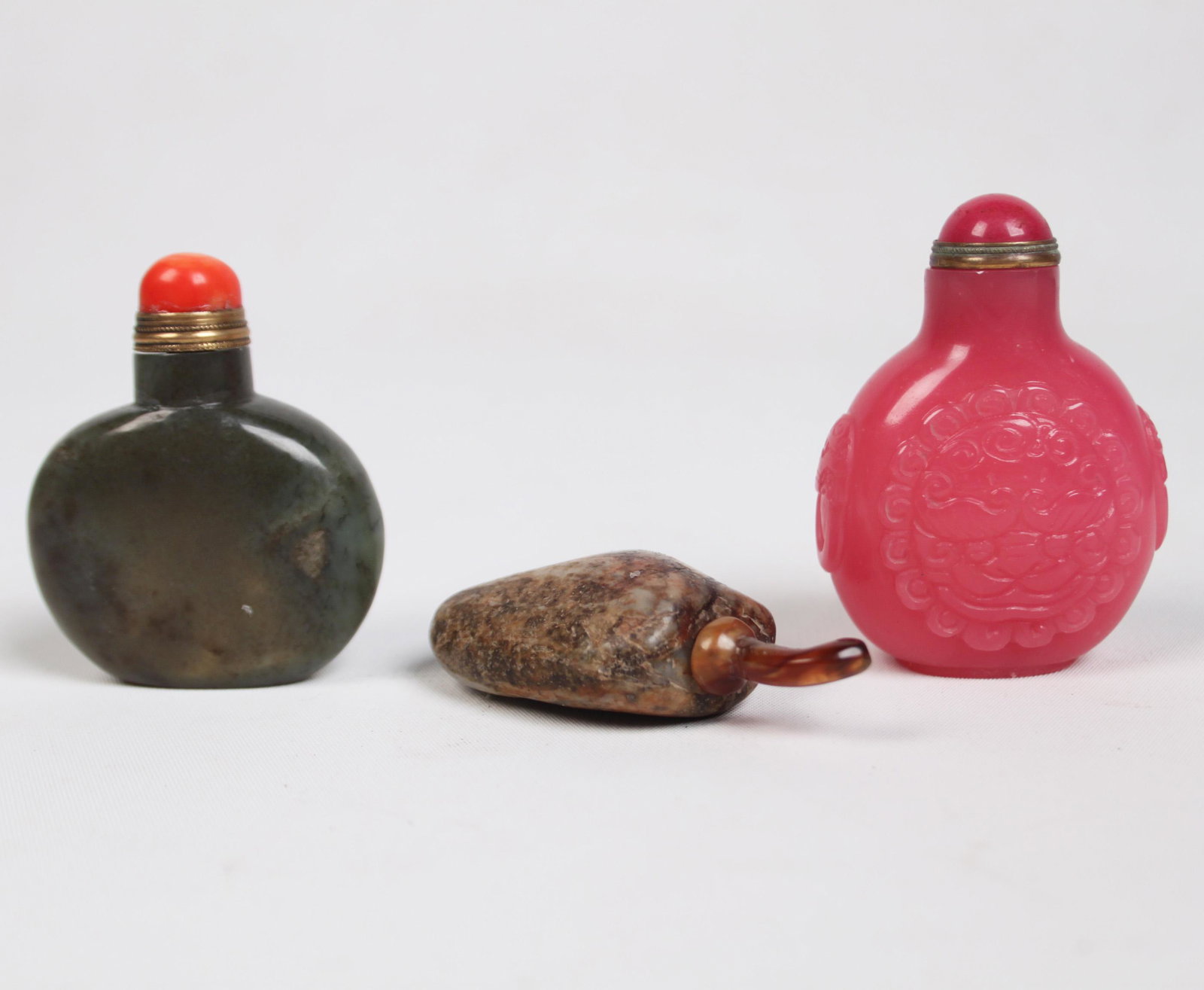 GROUP OF 3 MISC. CHINESE SNUFF BOTTLES: GROUP OF 3 MISCELLANEOUS CHINESE SNUFF BOTTLES CONSISTING OF A 2.5" GREEN JADE SNUFF BOTTLE WITH RED CORAL TOPPER AND BRASS SPOON, 1875-1920; A 2.5" JADE PEBBLE FORM SNUFF BOTTLE IN FREE FORM WITH AN 