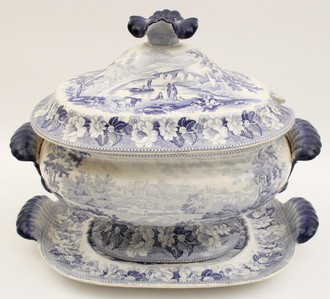 ENGLISH BLUE/WHITE COVERED TUREEN AND STAND: ENGLISH BLUE AND WHITE STAFFORDSHIRE STYLE COVERED TUREEN AND STAND HAVING PASTORIAL SCENE DESIGN WITH IMPRESSED MARK ON REVERSE (NOT LEGIBLE); 12"H X 15"W X 8"D; CONDITION: CHIP TO FOOT RIM OF TRAY