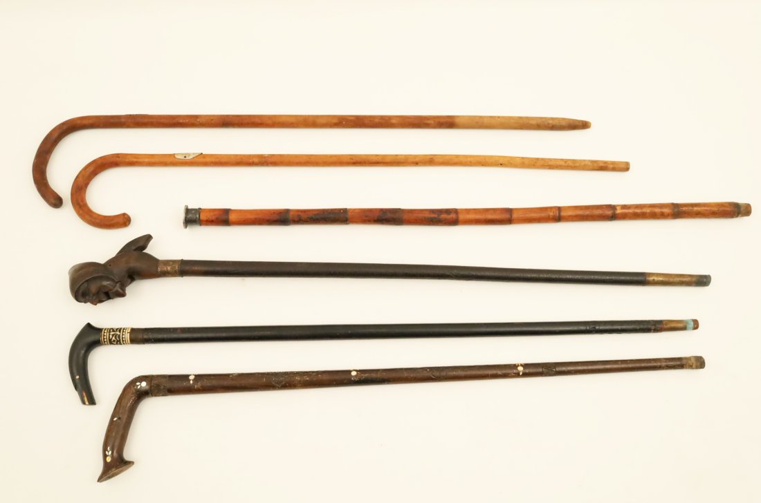 Group of 6 antique walking canes: Group of 6 antique walking canes, including a German figural nutcracker cane, two British Colonial canes with Asian influence bone and shell inlay, one bamboo cane with a 1897 Philippine Peso mounted 