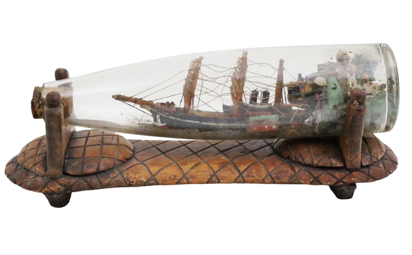 ORIENTAL SHIP MODEL IN BOTTLE ON STAND, 19TH C.: Oriental ship model in a bottle, resting on bespoke carved teakwood stand, late 19th century; 5"H 13"W 5"D