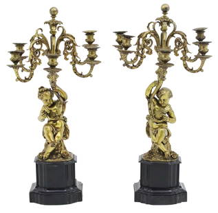 PR FRENCH GILT BRONZE FIGURAL CANDELABRA: Pair of French gilt bronze five light candelabra, the figural column depicting a pair of putti holding torchieres, mounted on black marble plinths, 19th century; 28"H 12"W 8"x6" base