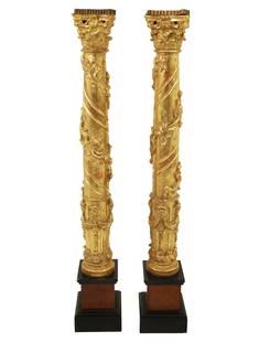 PR. OF 19TH C. ITALIAN GILTWOOD TORCHIERES: Italian carved giltwood torchieres having elaborate Corinthian caps and ribbed metal gallery resting on ebony and mahogany pedestals, 19th century; 65"H 8.5"W 8.5"D