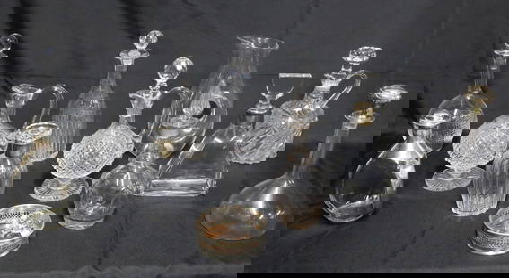 12 CUT CRYSTAL AND GLASS DECANTERS INCL. STERLING: Lot of twelve cut crystal and glass decanters, some with sterling silver collars and tops, along with a champagne coaster and additional stopper; largest 12"H smallest 8"H