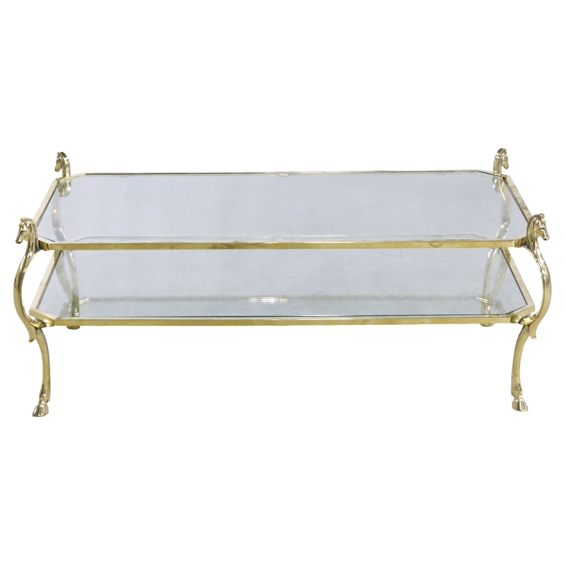 MAISON JANSEN GILT BRASS AND GLASS COFFEE TABLE: Maison Jansen gilt brass and glass two tier coffee or low table, having horse head surmounts and resting on hoof feet, early 20th century; 17.5"H 48"W 24"D